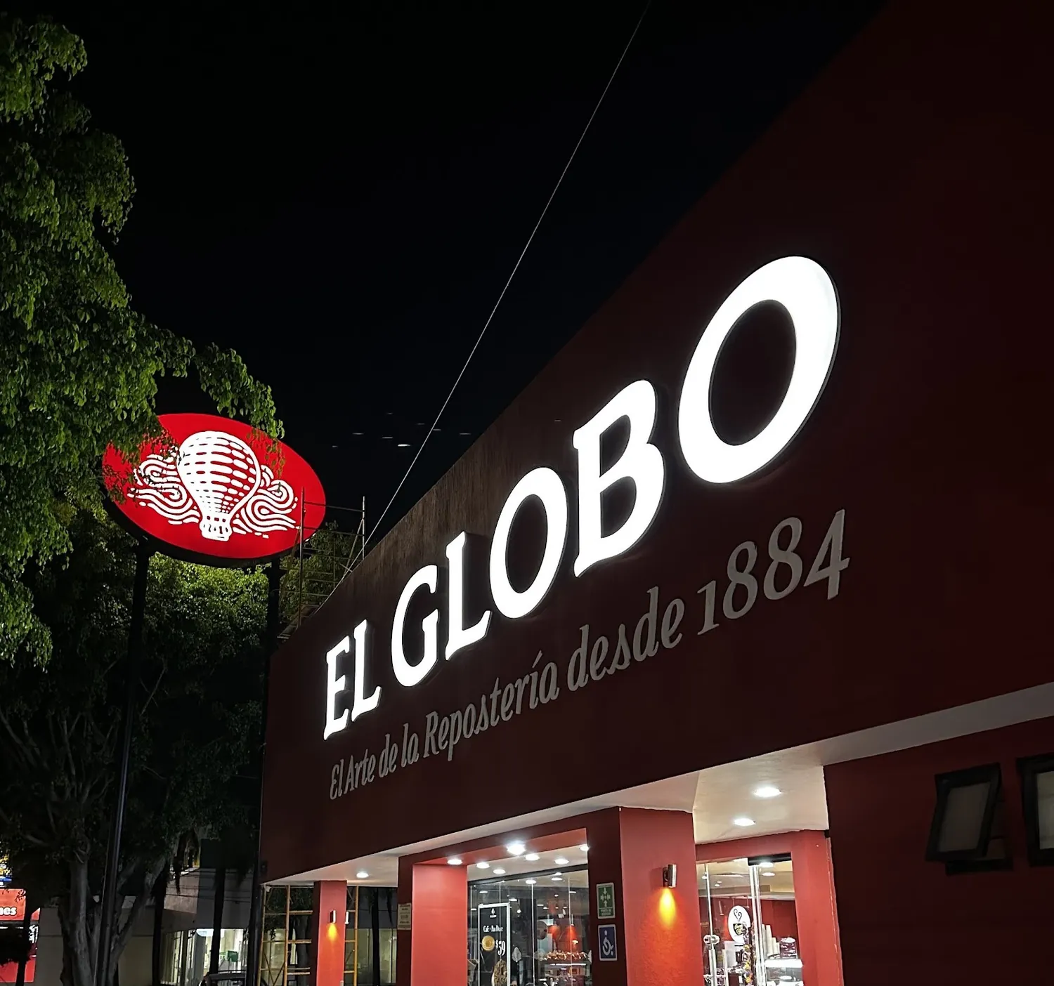Letras iluminadas de El Globo en la fachada de una sucursal, de noche