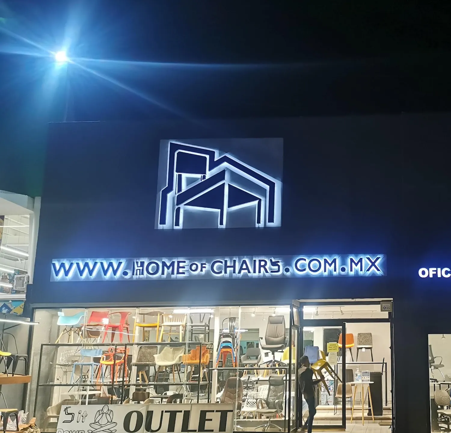 Fachada de Home of Chairs de noche, con logotipo y letras iluminadas fabricadas e instaladas por TOPSA