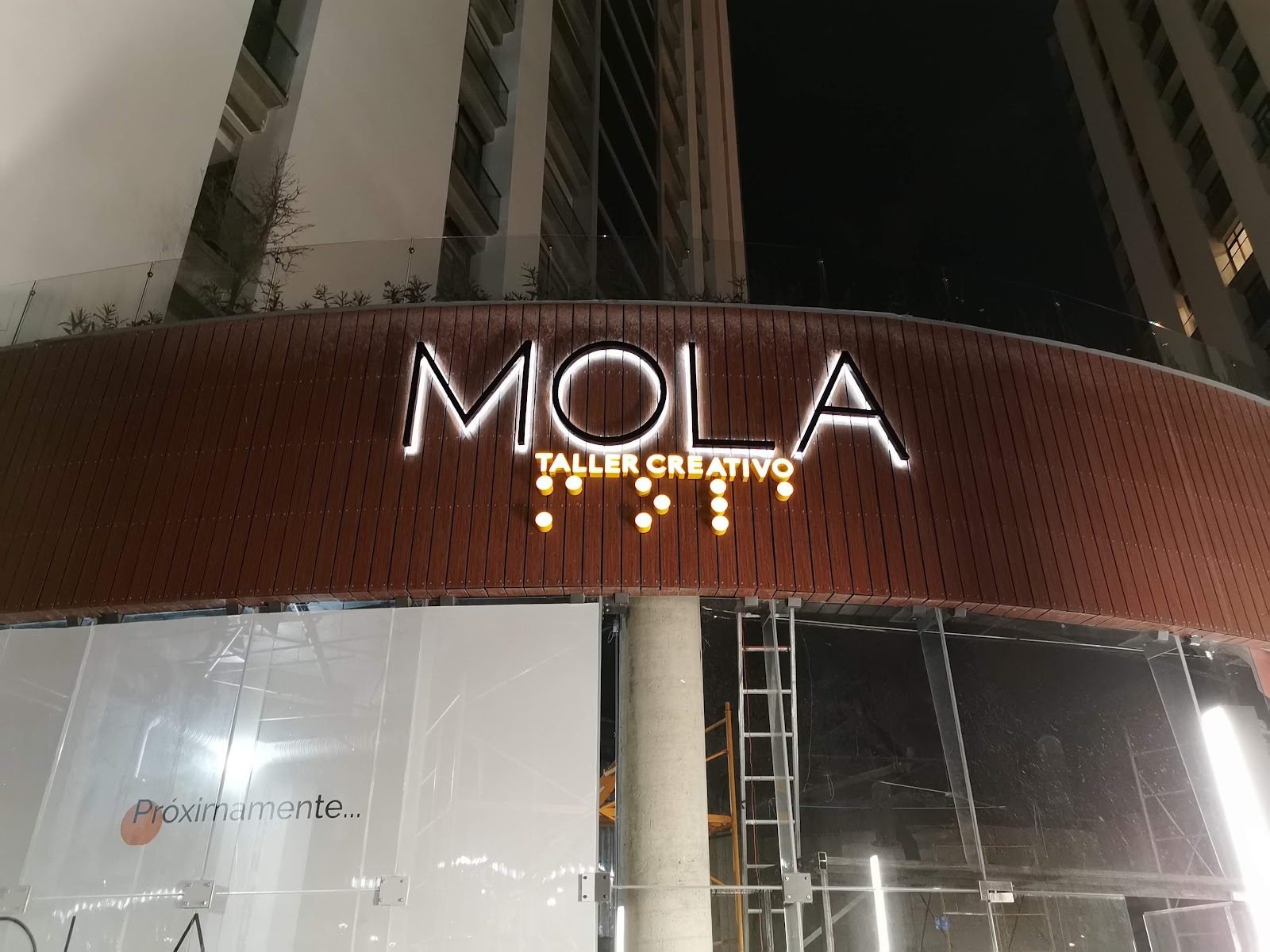Fachada curva de madera con letras iluminadas