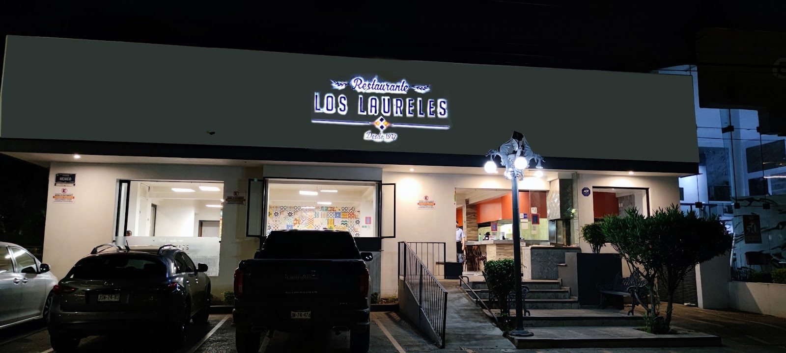 Letrero iluminado en la fachada de un restaurante, de noche
