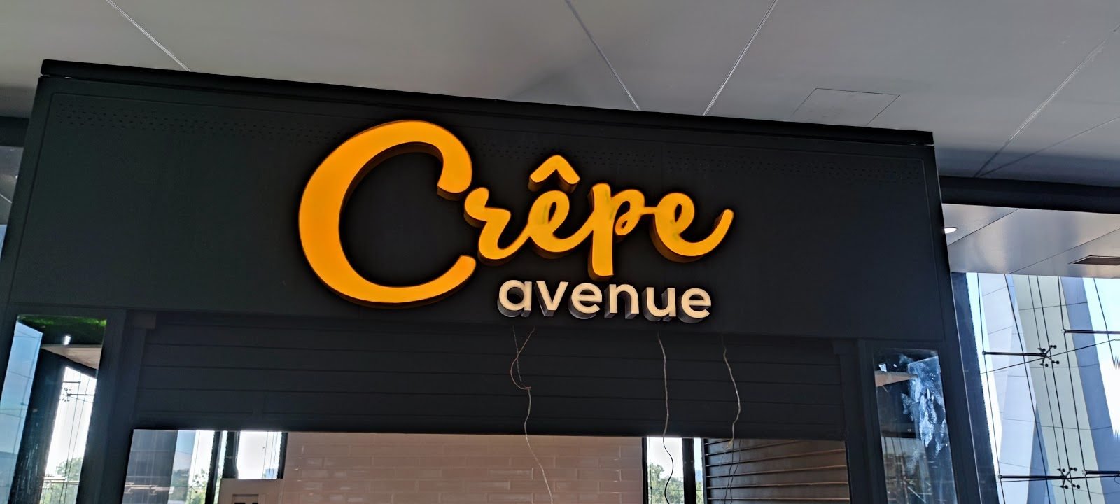 Fachada de panel oscuro con letras corpóreas amarillas