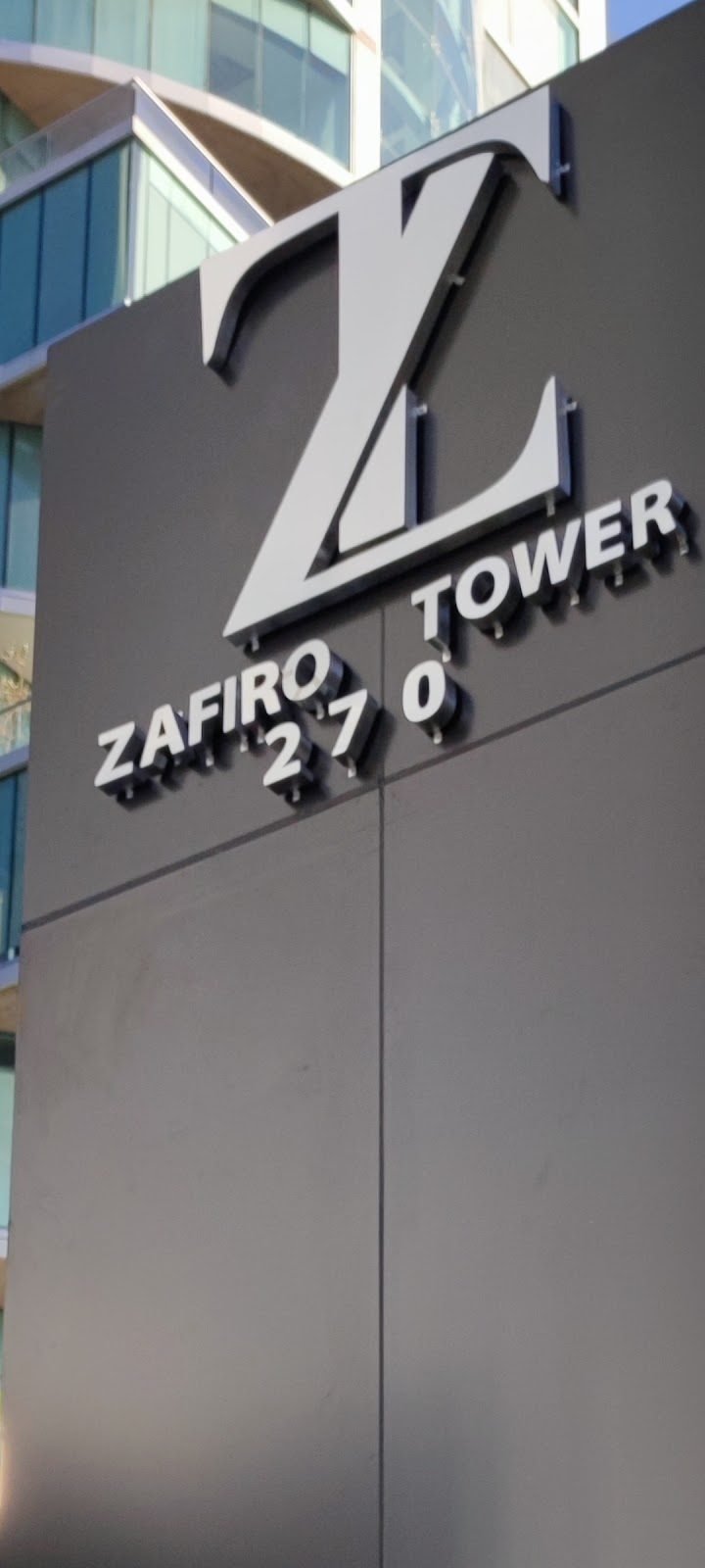Letras metálicas sobre panel de aluminio gris en torre corporativa
