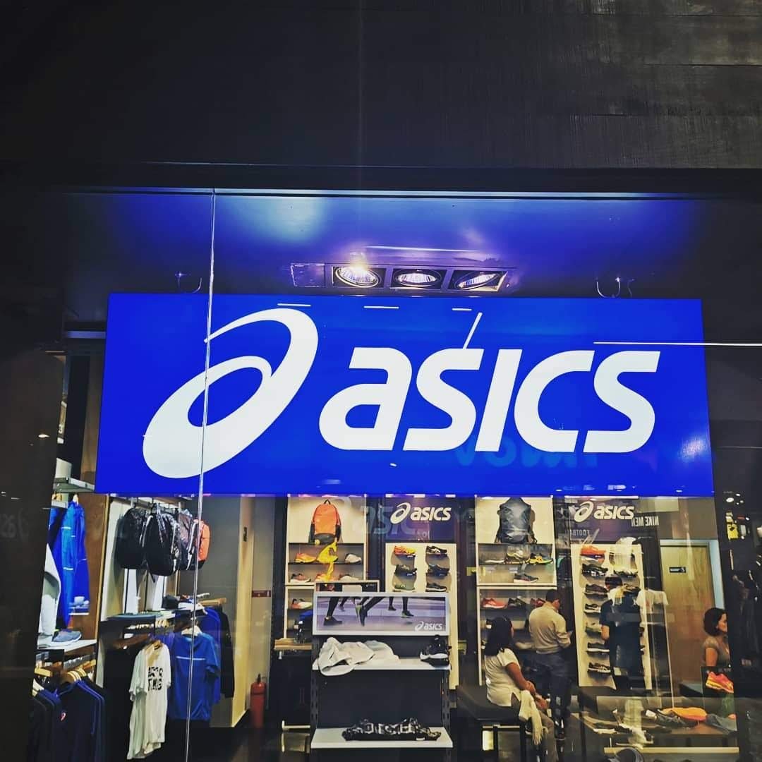Letras y logotipo iluminados sobre panel azul en tienda de plaza