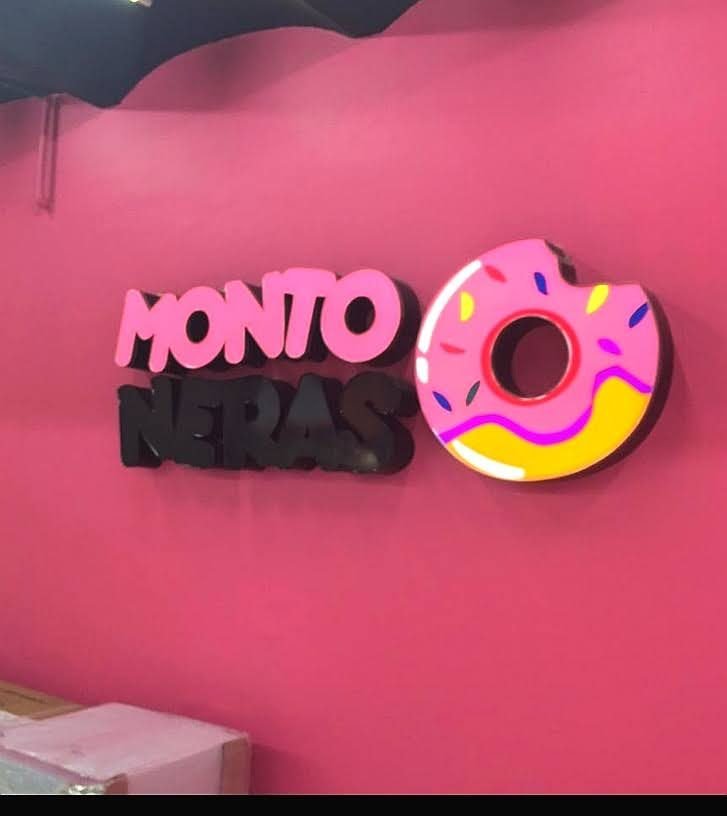 Letras 3D rosas y negras sobre muro de cafetería