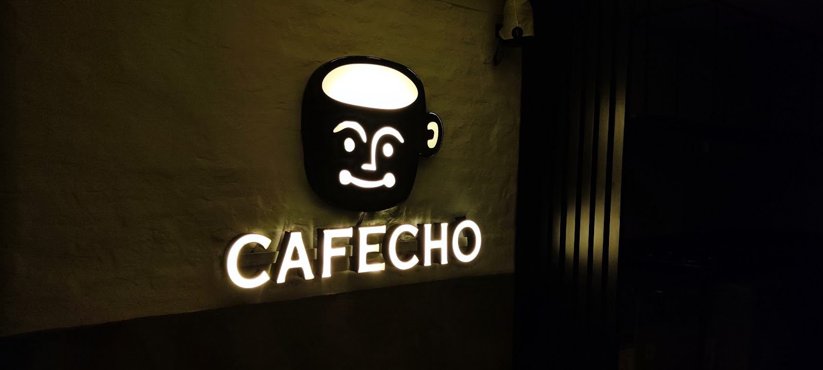 Logotipo y letras con luz frontal y halo sobre muro