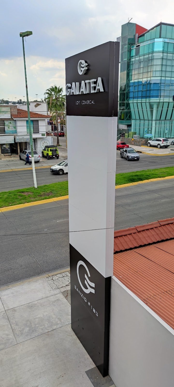 Tótem blanco y negro de plaza comercial sobre avenida